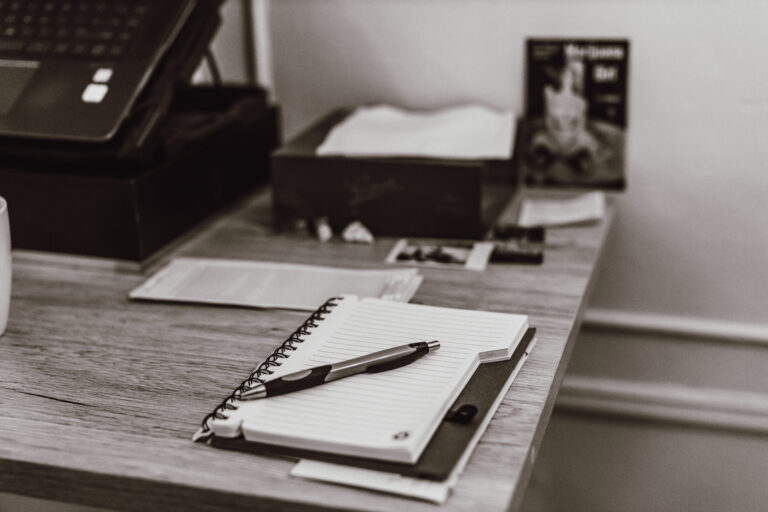 A notebook and pen on a desk beside a laptop, illustrating AWARD’s cannabis news coverage, media consulting, and media planning services.